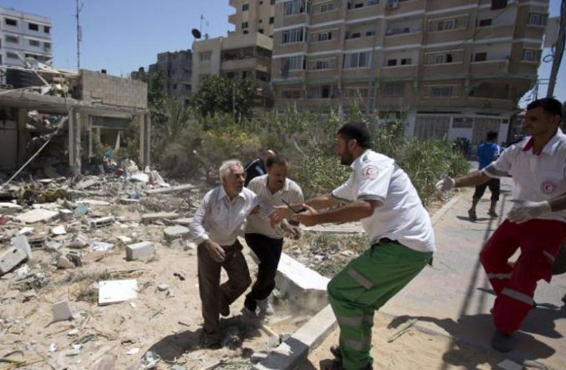 Palestinian medics help evacuate a survivor after an Israeli airstrike on his home in Gaza City on July 27, 2014. (Net)