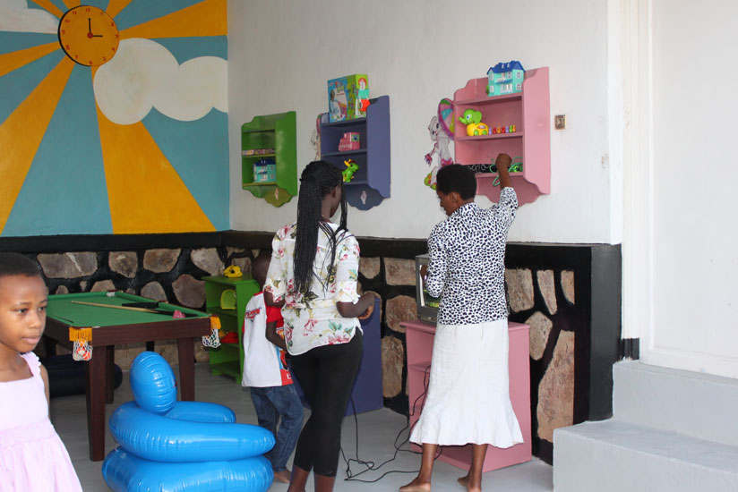 Teacher Jane Kalega (right)  picks a toy for a child. (Solomon Asaba)