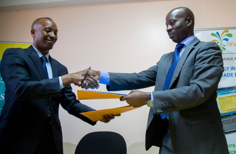 Seka (left) and Raphael Tugirumuremyi, the RRA Deputy Commissioner General in charge of customs exchange documents in Kigali on Monday. (Timothy Kisambira)