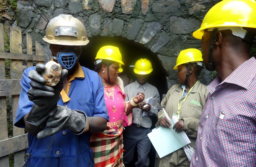 Members of the delegation with workers at Gifurwe Wolfram Mining Company look at the minerals as they get out of the tunnel on Tuesday. (Emmanuel Ntirenganya)