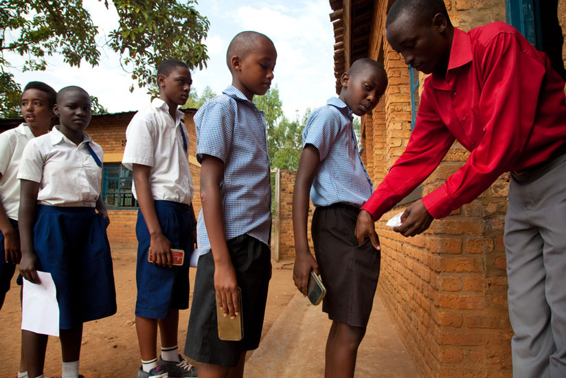 An invigilator checks pupils before they enter an examination room a few years ago. (Timothy Kisambira)