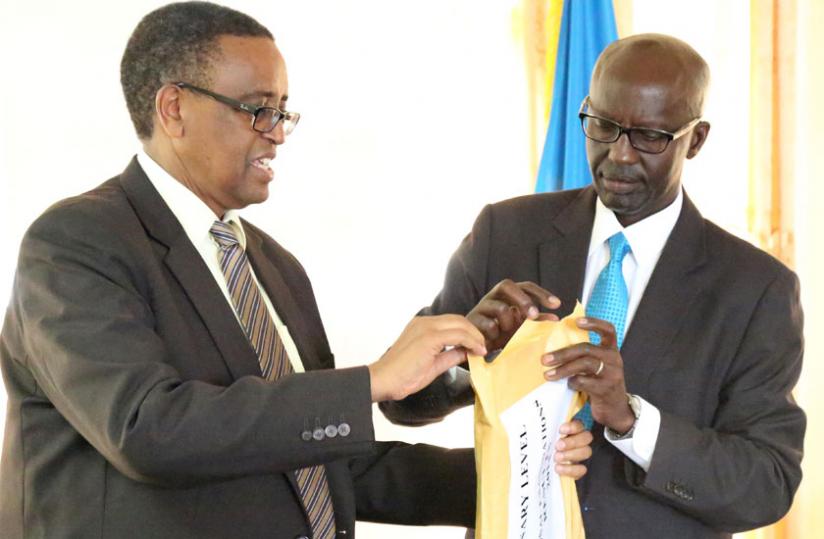 Education minister Silas Lwakabamba (L) and John Rutayisire, the director-general of Reb, open an envelope containing the 2014 O-Level results on Monday. (John Mbanda)