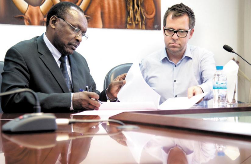 Kanimba (L) and Banks sign paperwork yesterday. (T. Kisambira)