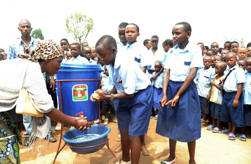 A woman joins Kagugu Primary School children in washing hands in 2012. Mineduc has launched a new school health policy and strategic action plan. (File)