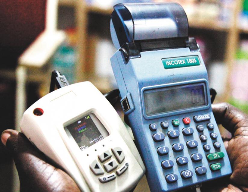 An agent displays an e-billing machine unit. Some agents are cheating customers by imposing illegal fees on the use of electronic cards to pay for services and goods.