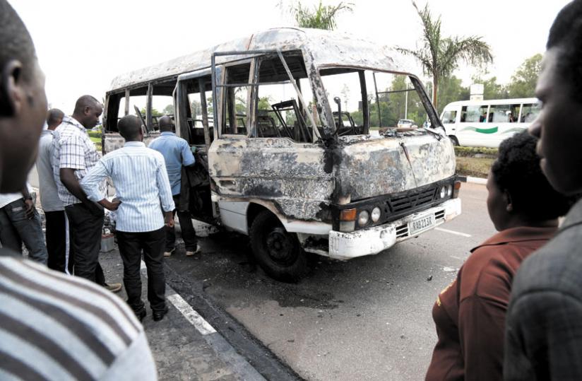 Onlookers at the scene of the fire assess what remained of the commuter omnibus yesterday. (John Mbanda)