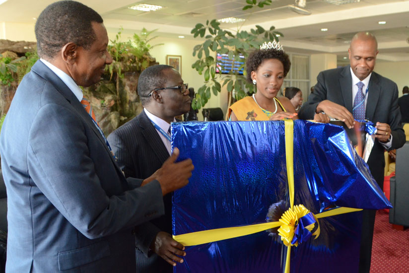 Uganda's Transport minister Eng. Abraham Byandala admires a gift presented to him by Mirenge (right) at Entebbe International Airport. Centre is Patricia Ntale, Uganda's Miss Tourism . 