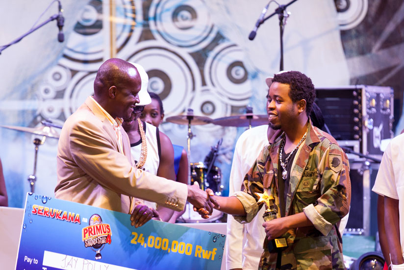 Jay Polly receives a dummy cheque from minister of sports and culture, Joe Habineza last year. Jay Polly was last year's winner of the Primus Guma Guma season 4 competition. He bagged Rwf 24m. (File)
