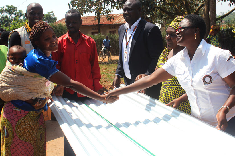 Leoncie Mukagasana (L),  from Maranyundu Cell, receives iron sheets from officials. (Michel Nkurunziza)rn.