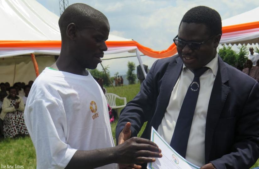 Charles Mutabazi (L) receives a certificate from Nyaruguru Mayor Franu00e7ois Habitegeko, at the literacy graduation in Nyaruguru District yesterday.(Emmanuel Ntirenganya)