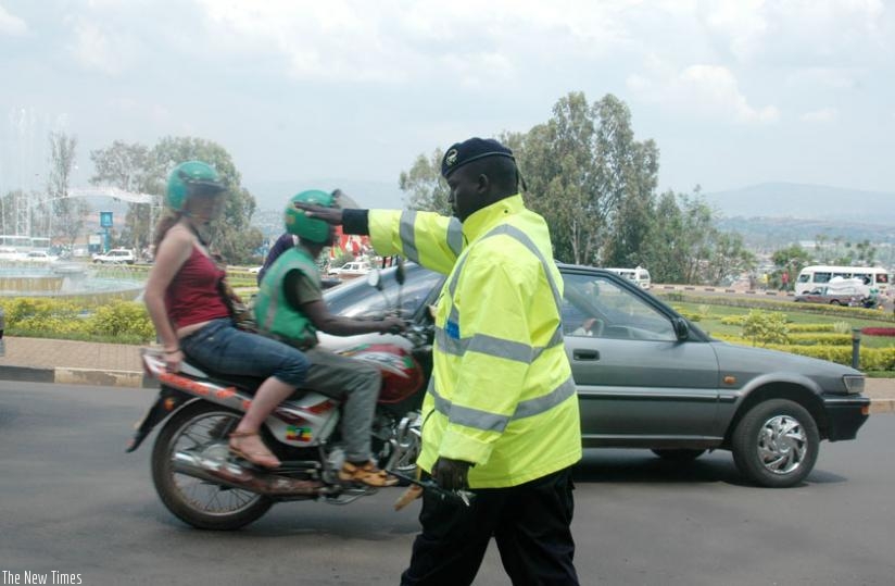 A Traffic Police officer flags down a car for routine inspection on a street in Kigali. (File)