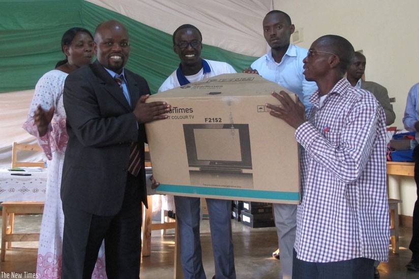 The Minister of Youth and ICT, Jean-Philbert Nsengimana (L) awards a teacher during one of the ICT awareness campaigns.