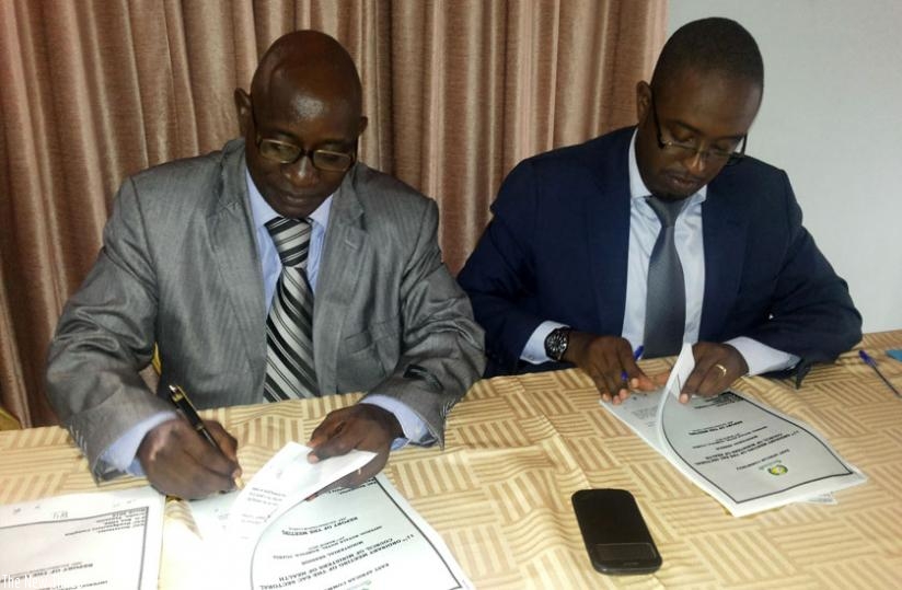 Uwaliraye (R) and Jean Rigi, Burundiu2019s Permanent Secretary in the Ministry of EAC Affairs, sign documents in Kampala, Uganda, yesterday. (G. Muramila)