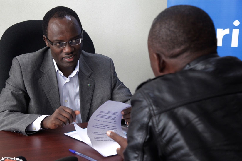 Ndayisaba attends to a resident seeking service.  (John Mbanda)