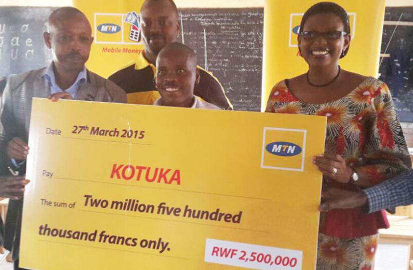 Asiimwe (right) hands over a dummy cheque to KOTUKA and Kanama sector leaders on Friday. (Courtesy)