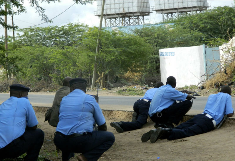 Kenyan police officers take cover outside the Garissa University College during an attack by gunmen. 