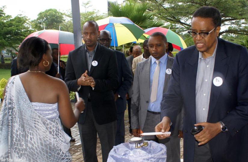 Minister Silas Lwakabamba (R) lights a candle as State ministers Olivier Rwamukwaya (C) and Albert Nsengiyumva look on. (Courtesy)