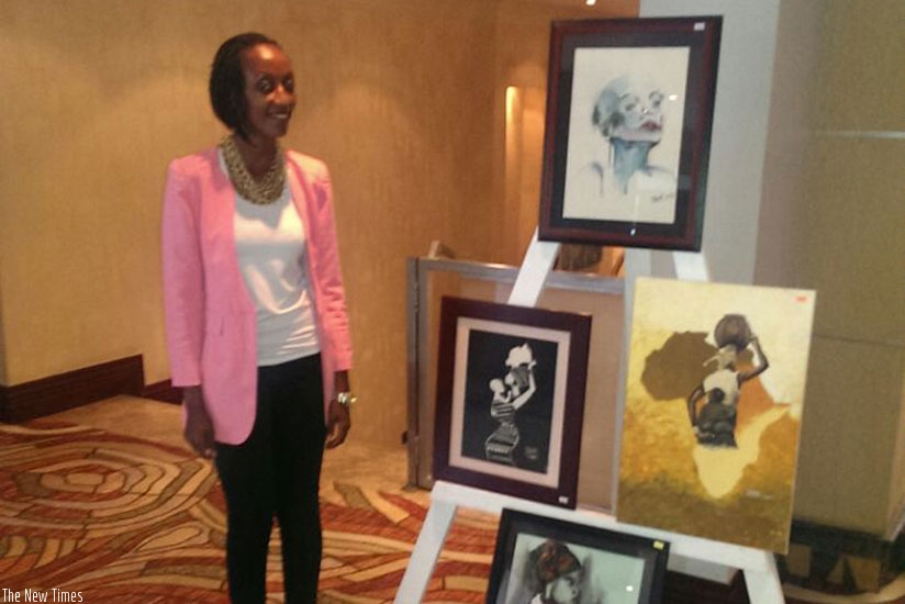 Pearl Karungi, one of the painters,  stands next to some of her work.