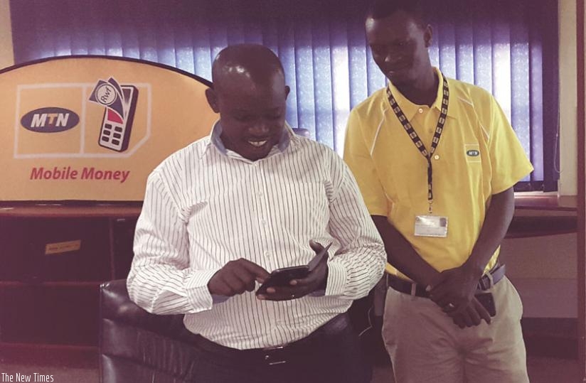 Emmanuel Butare, the headmaster of GS Muyange, tries out how one can pay school fees using mobile money yesterday at MTN head office in Nyarutarama. (Courtesy)
