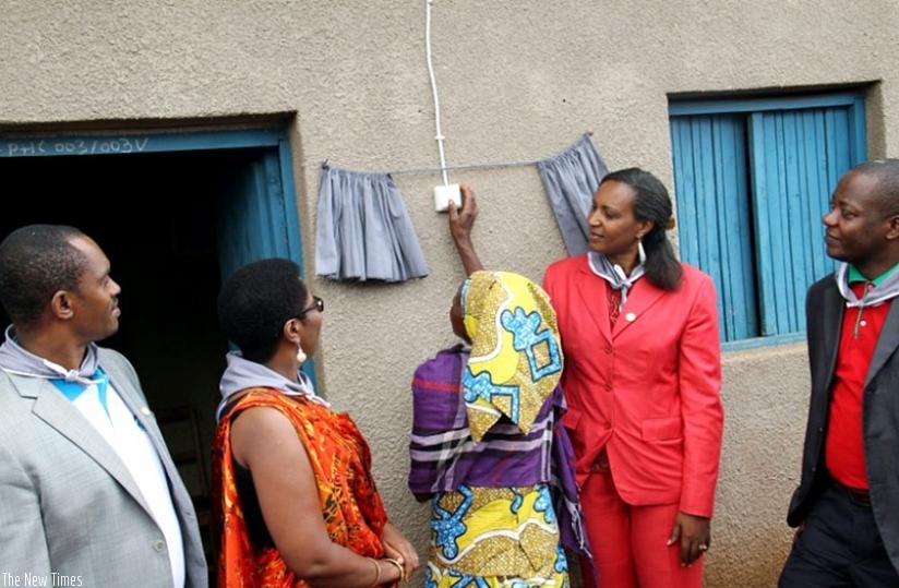 Mukamusigwa turns on a switch after her home was connected to electricity. (Michel Nkurunziza)