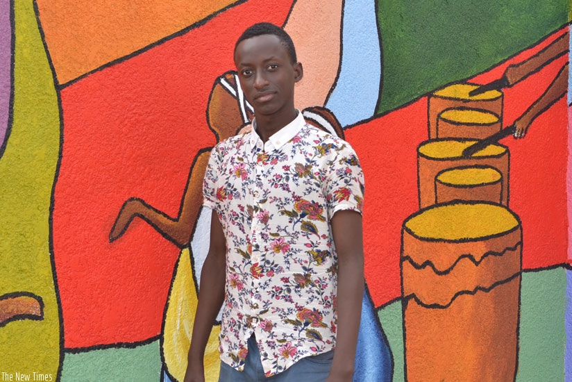 Tresor Kwizera poses for a photo next to one of his paintings. (Stephen Kalimba)