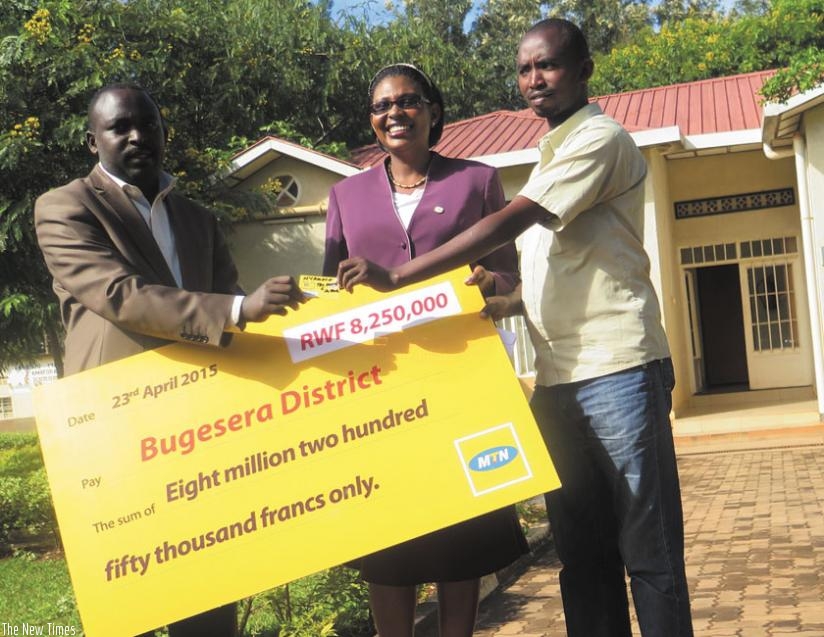 ETO deputy head teacher in charge of discipline, Gasana Etienne (right), at receives a mobile money-enabled SIM card from Rwagaju and Asiimwe at the district head offices. The students' fees will be sent using mobile money transfer service. (Jean Nepo Ndikumana)