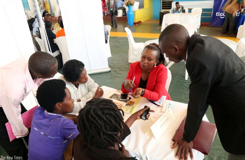 Job-seekers speak with a potential employer at the job fair in Remera on Tuesday. (John Mbanda)