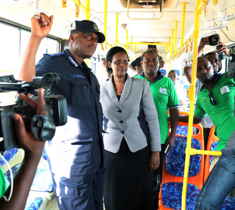 Gender Minister Oda Gasinzigwa (C) with Commissioner of Police Emmanuel Butera (L) and KBS Chairman Charles Ngarambe watch an onboard video message in a bus yesterday. (John Mbanda)