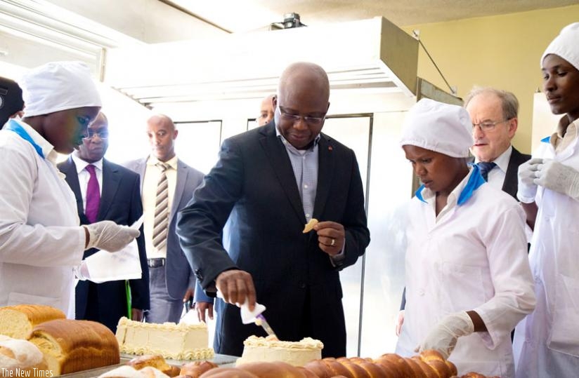 Ivorian State Minister for Employment and Professional Training Moussa Dosso (C) tastes on one of the cakes made at Nyarutarama Vocational and Business Incubation Centre yesterday. (Timothy Kisambira)