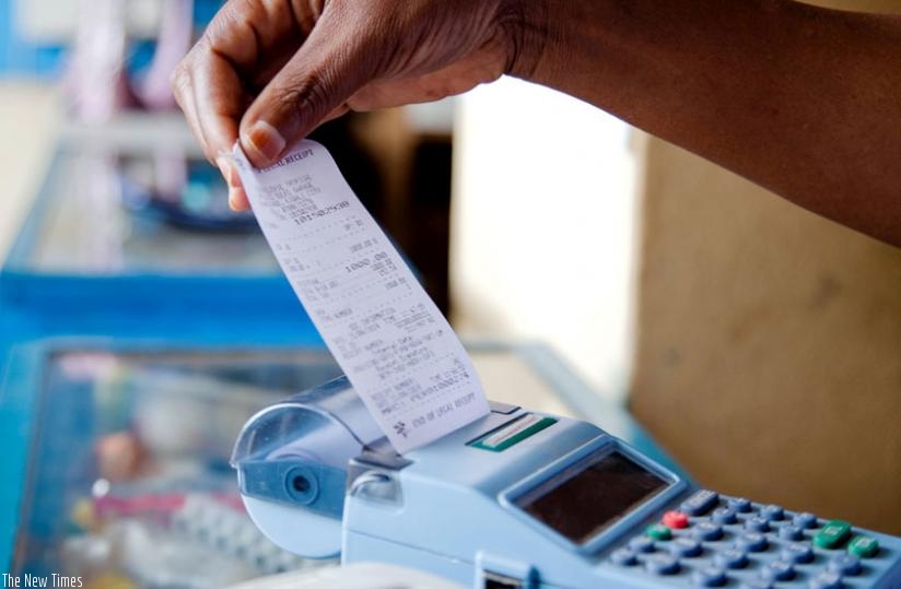 A trader pulls a receipt out of an e-Billing machine. Electronic billing was introduced to curb tax evasion and boost revenue collection. (File)