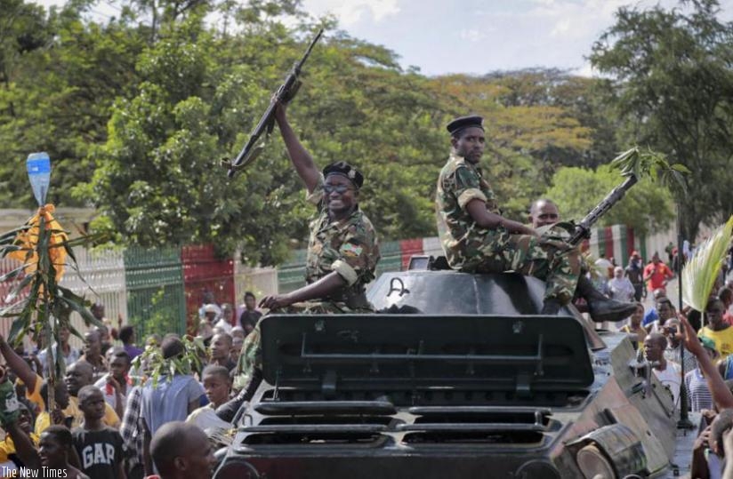 A Burundian soldier riding in an armored vehicle raises his gun in the air as he joins demonstrators celebrating a coup attempt against President Pierre Nkurunziza, in the capital Bujumbura, yesterday. (Net photo)
