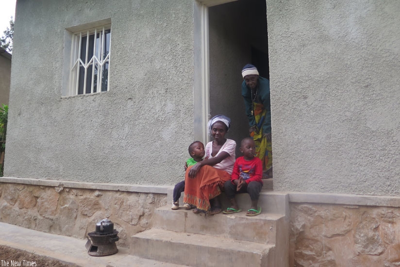 Family of Therese Umwanayezu sit in front of their newly renovated home. (Frederic Byumvuhore)