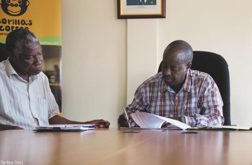 Uwimana (right) signs the funding agreement at NAEB head offices on Tuesday as Dukundekawa-Musasa Co-operative's Minani (left) looks on. (Timothy Kisambira)