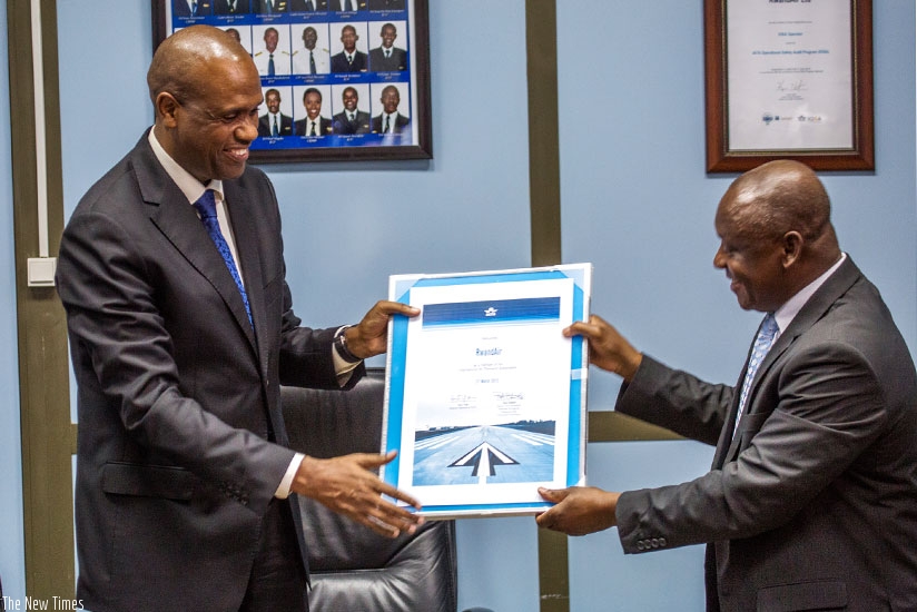 RwandAir CEO John Mirenge (L) receives a certificate from Raphael Kuuchi, the vice president of International Air Transport Association at Kigali International Airport yesterday. (All photos by Timothy Kisambira)