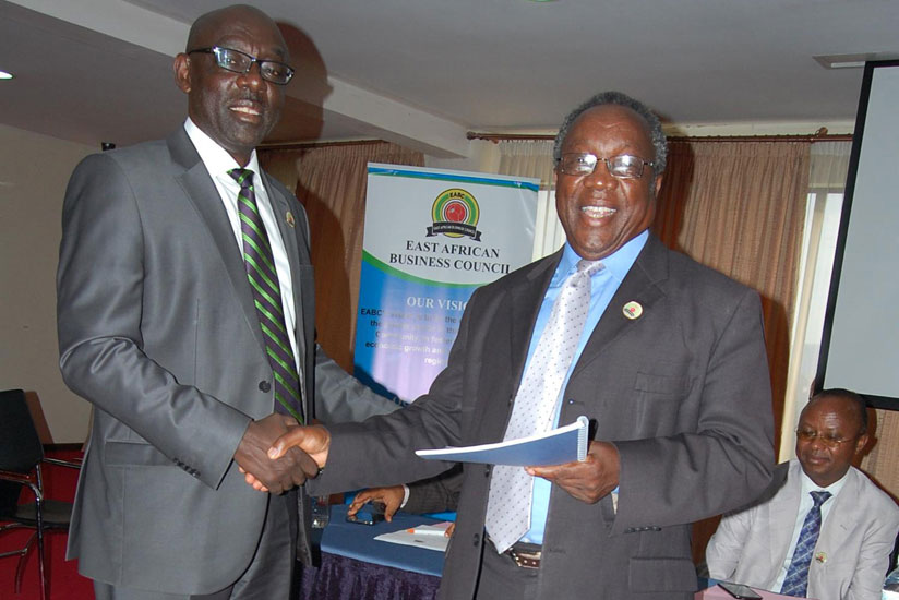 New East Africa Business Council Chairman Dennis Karera (L) receives documents from Felix Mosha, the outgoing EABC chairman. (Peterson Tumwebaze)