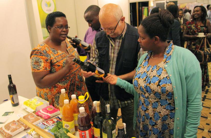 Christine Murebwayire (left) explains about her banana wine at an exhibition last year. NIRDA is supporting production of banana wine and juice. (File)