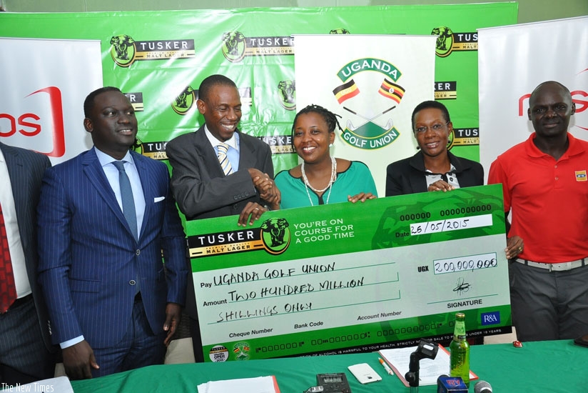 Grace Nshemeire Gwaku (C), Marketing Director UBL  hands over a dummy check for sponsorship of 2015 Uganda Open to Kiryowa Kiwanuka, the president UGU. (Courtsey)