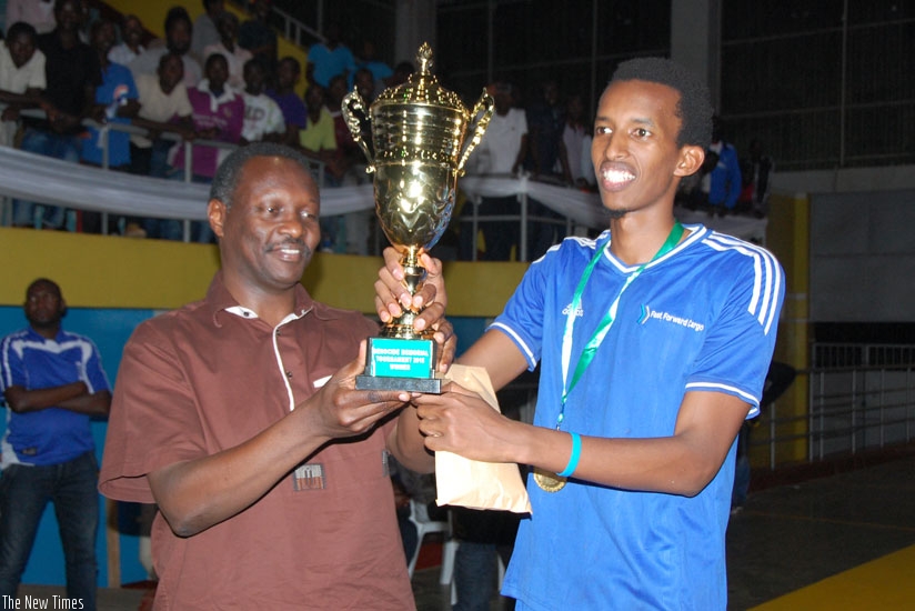 Rwanda National Olympic and Sports Committee president Robert Bayigamba hands over the trophy to Rayon Sports captain Fred Musoni at Amahoro stadium yesterday.  Courtesy