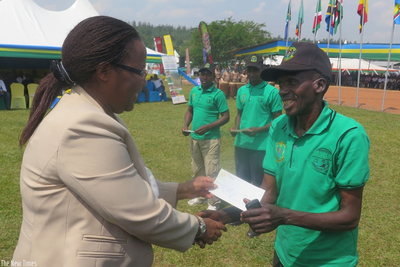 A farmer receives a cheque of Rwf100,000 from minister Mukeshimana. (Moses Opobo)
