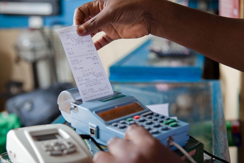 A trader pulling a receipt out an electronic billing machine. RRA is keen on having every trader use the machine to increase efficiency in collecting taxes. (Timothy Kisambira)
