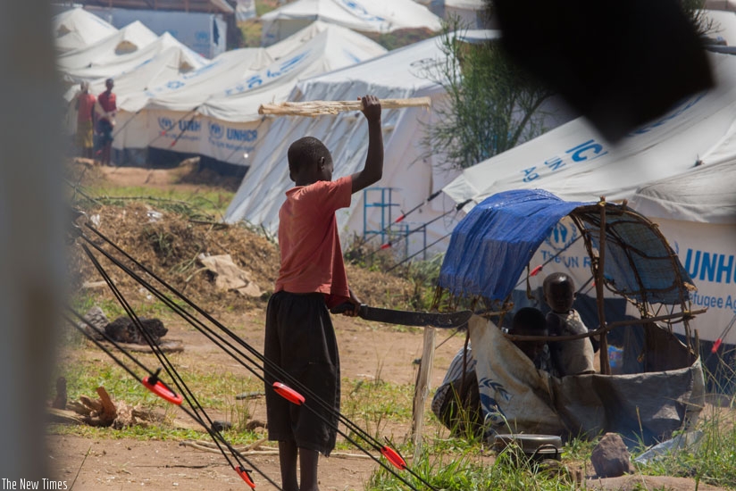 A child at Mahama refugee camp splits firewood to prepare a meal. (Timothy Kisambira)