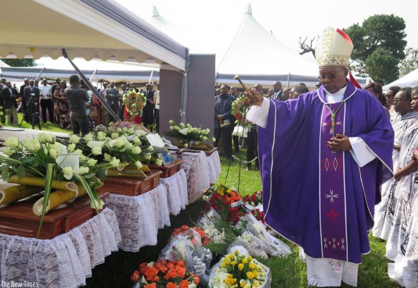 Monsignor Philip Rukamba, the Bishop of Butare Cathedral, sprinkles holy water on caskets containing the remains of some of the Genocide victims before their burial on Sunday.  (Emmanuel Ntirenganya)