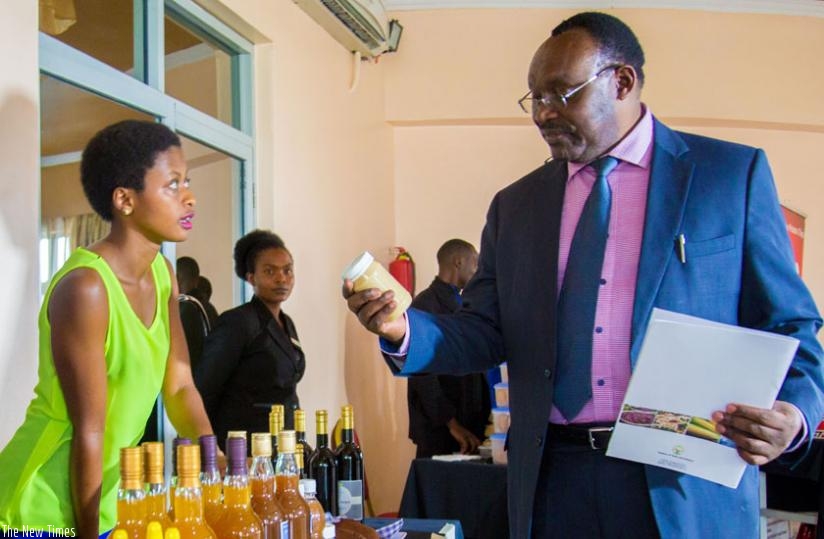 Belise Izabayo (L), marketing officer, Bio Hap Ltd, explains to Trade Minsiter Kanimba the different products they make from bananas during an SMEs exhibition in Kigali. (Doreen Umutesi)