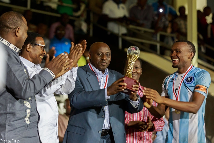 Inspector General of Police (IGP) Emmanuel Gasana (C) hands over the 2015 Peace Cup trophy to Police FC Captain Jacques Tuyisenge yesterday at Amahoro Stadium. (Timothy Kisambira)