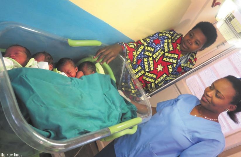 Mukayigira  (the mother)  and  Uzamukunda (R) admire the newborns. (Stephen Rwembeho)