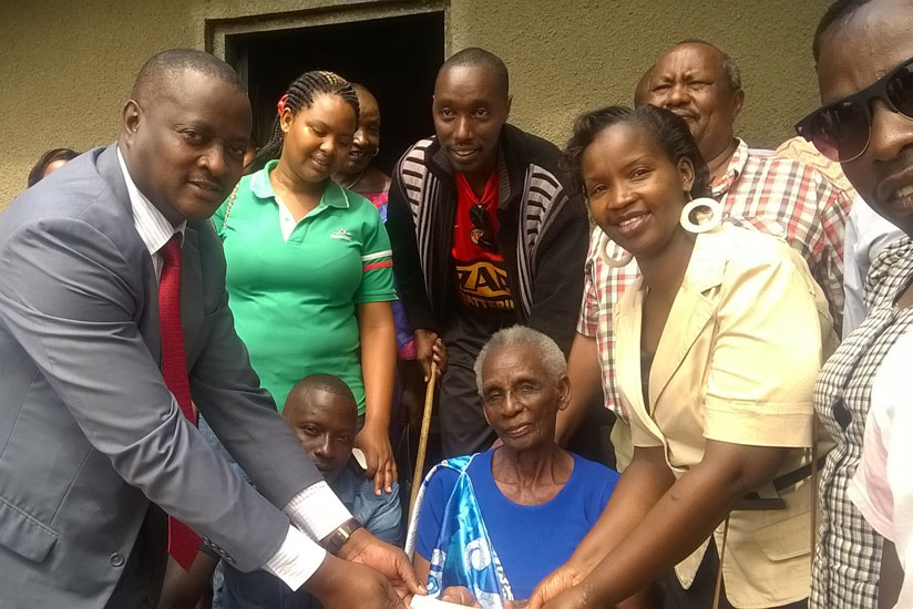 Lt Col Burabyo (L) hands over RDF's contribution to Kakindi (C ). Looking on are members of the Rwandan community in Entebbe, Uganda. (Gashegu Muramira)rn