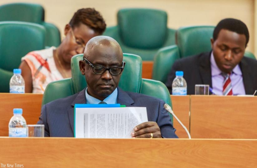 Minister Busingye checks through his documents while appearing before the Senate yesterday. (Timothy Kisambira)