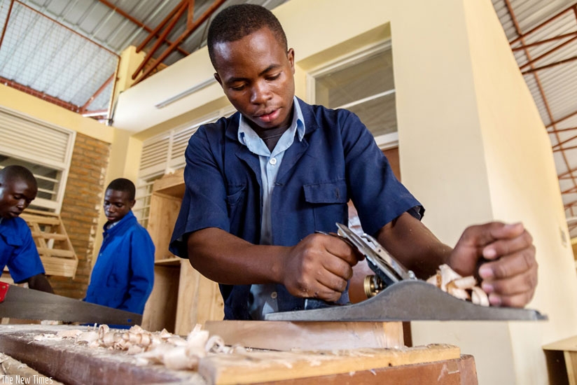 Aldo Ruzigamanzi, an 18-year-old VTC Muganzi student, files wood to make a chair. (Timothy Kisambira)