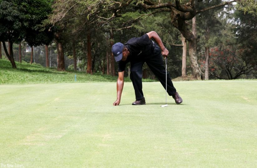 A golfer picks a ball from a hole at Nyarutarama golf course. (Timothy Kisambira)