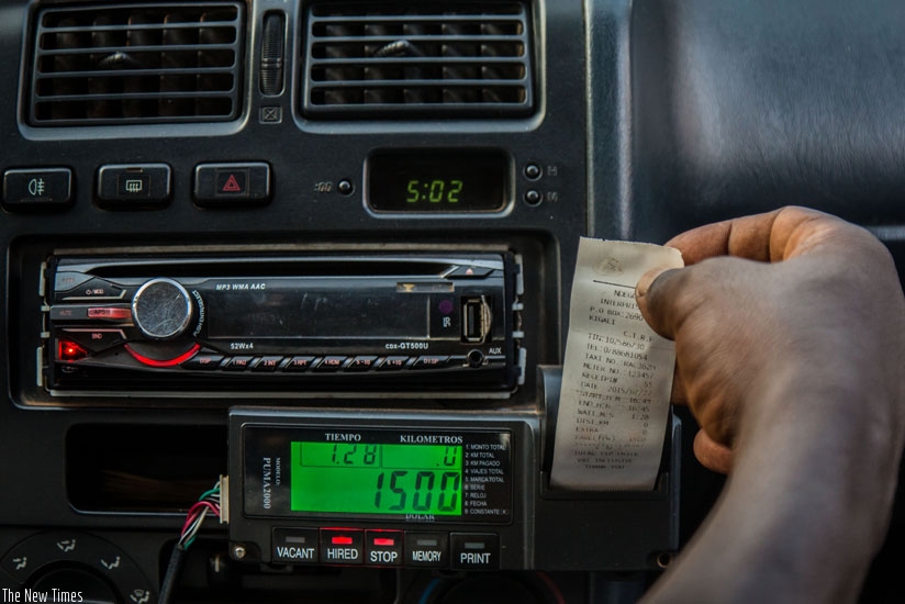 A cabdriver outside King Faisal Hospital Kigali prints a receipt from a taximeter for a passenger yesterday. The taximeter is used to determine how much a passenger should pay. (Timothy Kisambira)